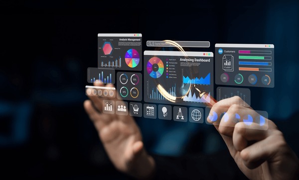A person interacts with a virtual dashboard displaying colorful charts, graphs, and data analytics on a transparent screen, using their hands to navigate the digital interface in a dark, modern environment.